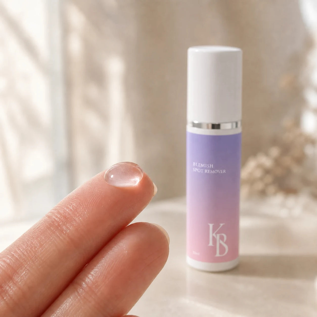 A clear bead of Kaloneo Beauty Blemish Spot Remover on a fingertip beside the 30ml bottle, showing the lightweight transparent gel