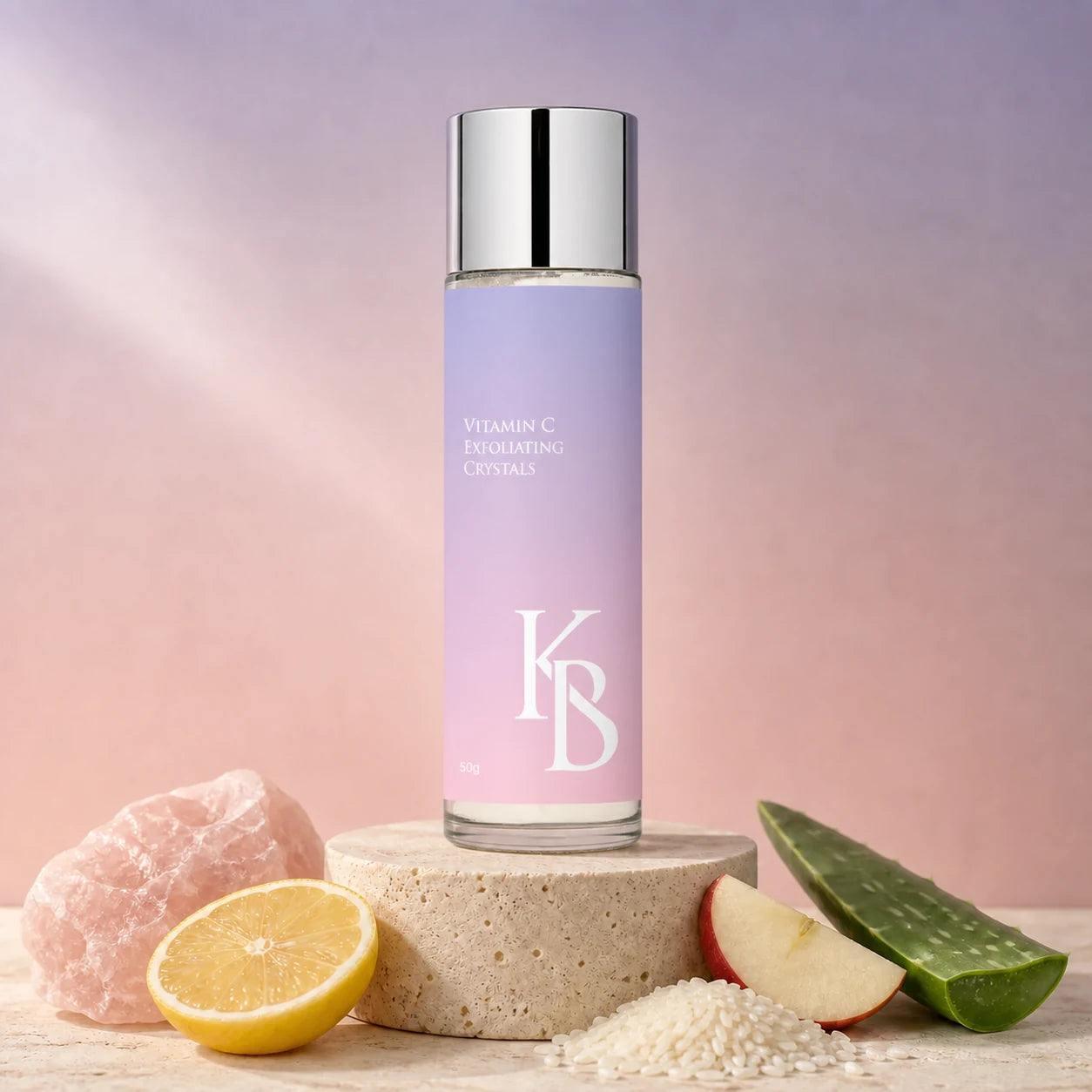 Kaloneo Beauty Vitamin C Exfoliating Crystals 50g on a stone plinth with rose quartz, lemon, rice, apple and aloe vera, the ingredients used in the formula