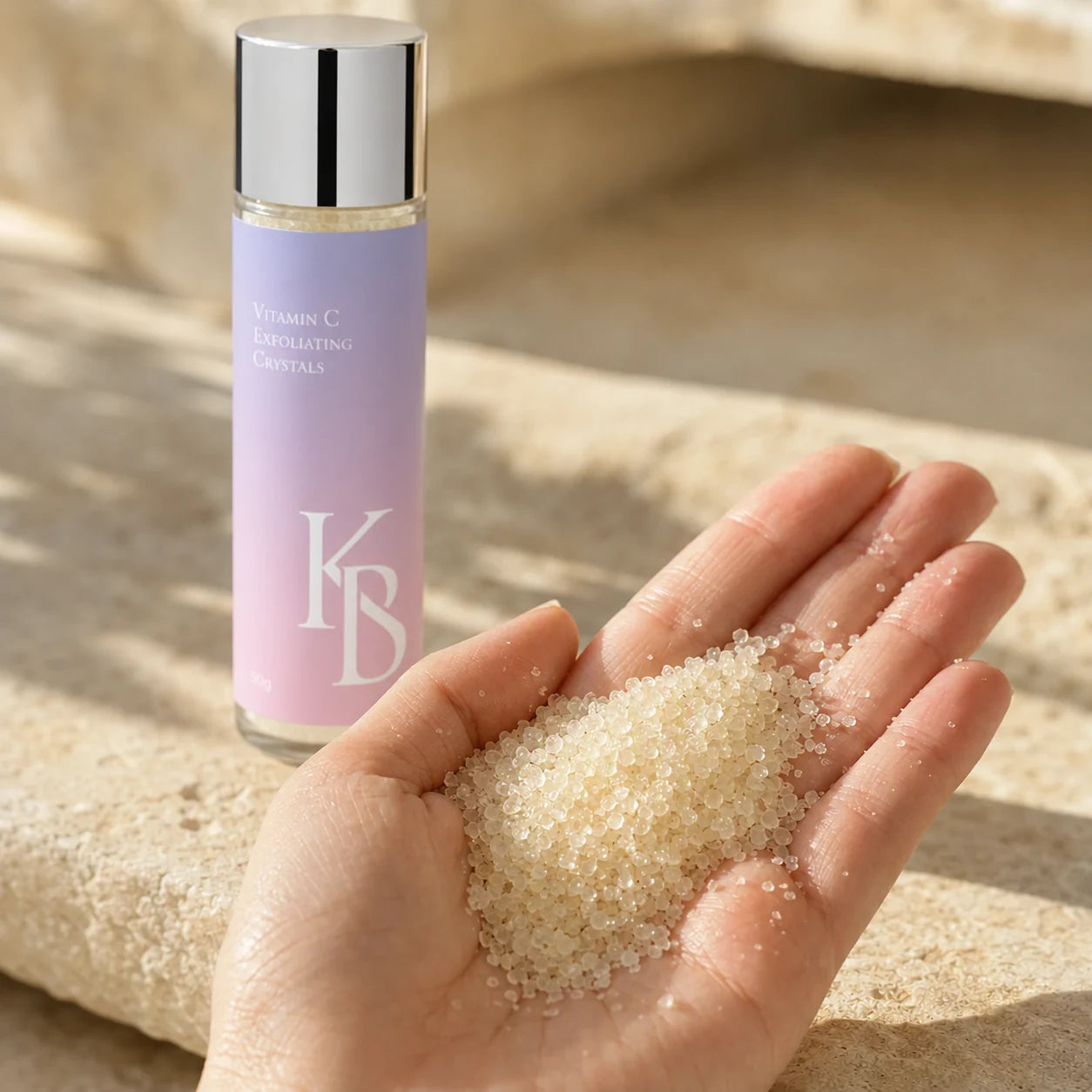 Close-up of Kaloneo Beauty Vitamin C Exfoliating Crystals in an open palm, translucent pearl-like exfoliating granules