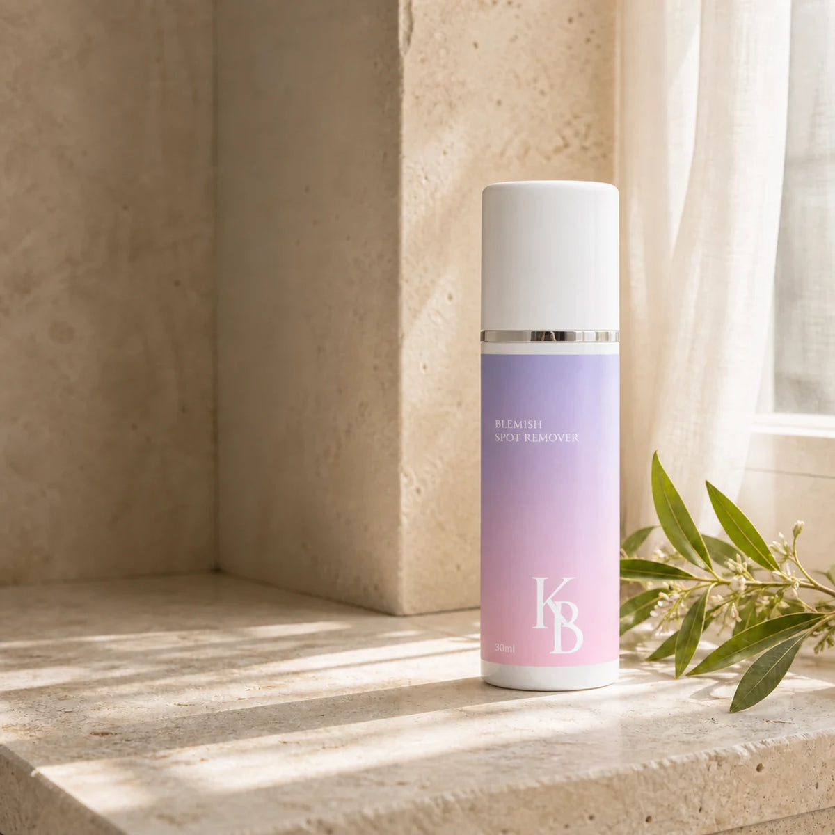 Kaloneo Beauty Blemish Spot Remover 30ml standing on a travertine ledge in morning light, a sheer curtain behind and a sprig of tea tree beside it