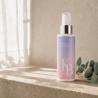Kaloneo Beauty Renewing Gel Cleanser 125ml standing on a travertine ledge in morning light, a sheer curtain casting soft shadows and a eucalyptus sprig beside it