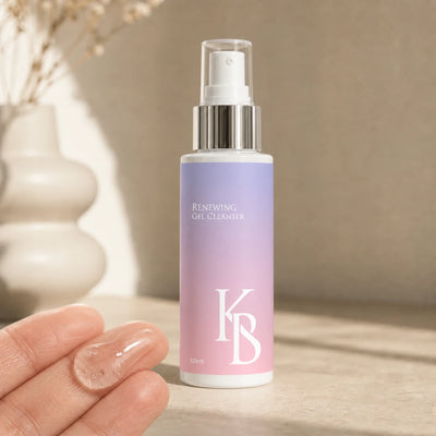 A clear bead of Kaloneo Beauty Renewing Gel Cleanser resting on open fingertips beside the 125ml bottle, showing the lightweight transparent gel