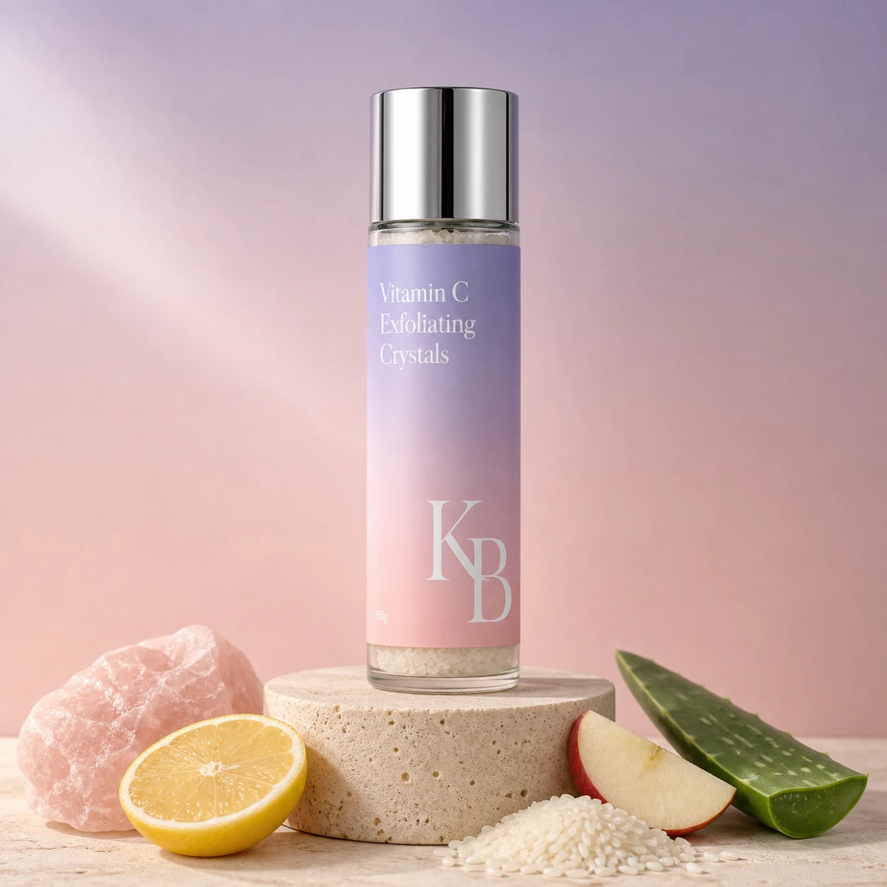 Kaloneo Beauty Vitamin C Exfoliating Crystals 50g on a stone plinth with rose quartz, lemon, rice, apple and aloe vera, the ingredients used in the formula