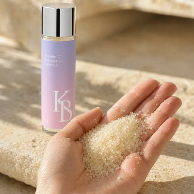 Close-up of Kaloneo Beauty Vitamin C Exfoliating Crystals in an open palm, translucent pearl-like exfoliating granules