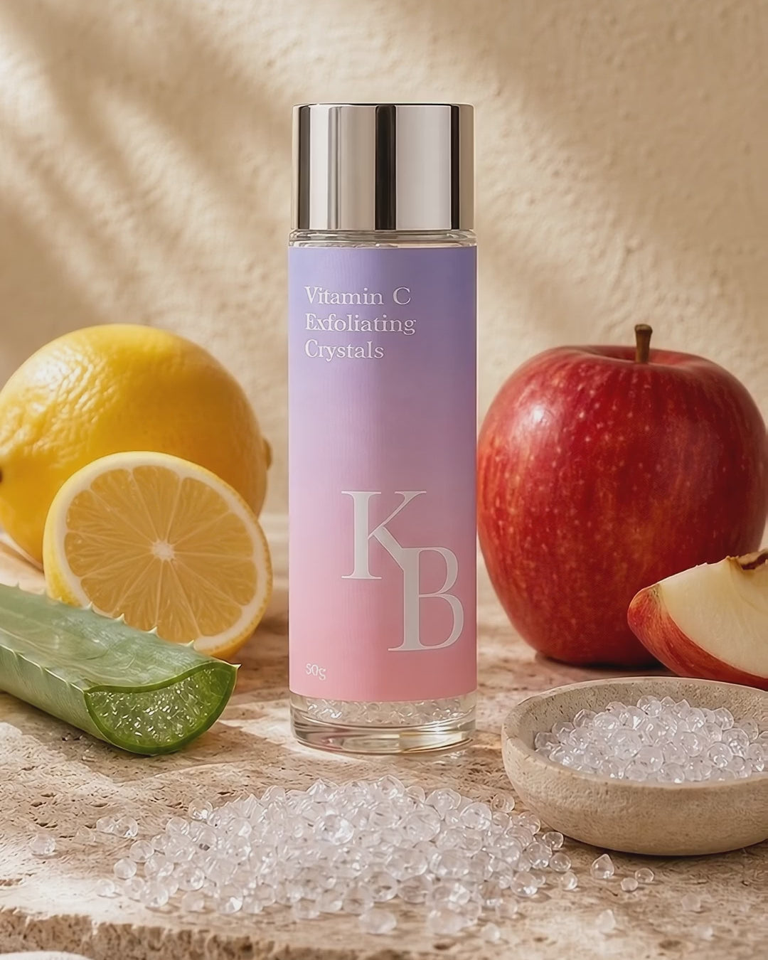 Load video: Kaloneo Beauty Vitamin C Exfoliating Crystals on travertine stone with the loose crystals, lemon, red apple and aloe vera in warm morning daylight - portrait product film with music